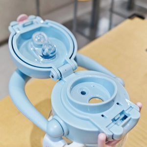 Close-up of pink and blue plastic water bottle lid with handle and straw detail
