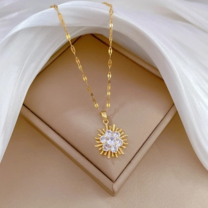 Elegant gold titanium steel necklace with sparkling sunflower pendant on silk background