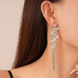 Detail of silver brushed flower tassel earrings worn by a model in a close-up profile view
