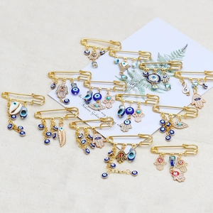 Detailed set of twelve gold-tone brooches featuring Hamsa hands and blue evil eye charms