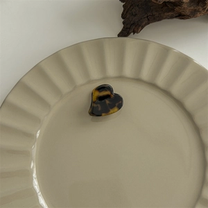 Detail of a heart-shaped tortoise shell claw clip on a stylish beige ceramic plate