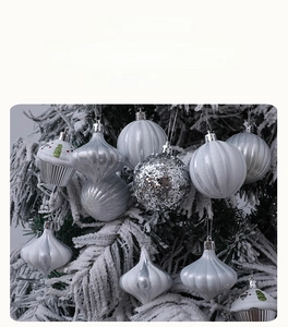 Detailed view of silver cupcake and droplet shaped Christmas ornaments on a snowy tree