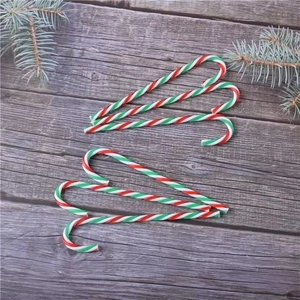 Macro shot of red, white, and green striped Christmas candy canes on dark wooden surface
