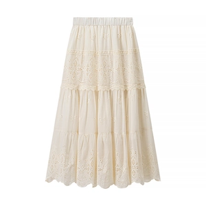 Detail of bohemian cream maxi skirt with delicate hollow-out embroidery and tiered layers