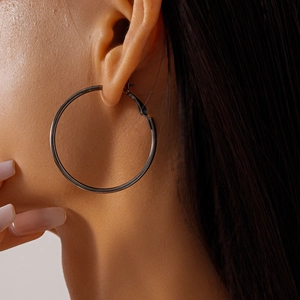 Close-up of model wearing large polished silver hoop earrings with a sleek geometric design