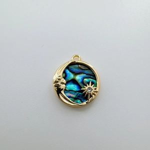 Detailed macro view of 18K gold-plated round abalone shell pendant with moon and star