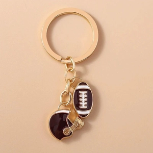 Golden metal keychain featuring brown rugby ball and helmet enamel charms on a ring