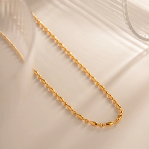 Collana in acciaio inossidabile placcata oro 18K con grani ovali su sfondo minimalista