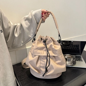 Détail du sac seau beige en nylon avec cordon de serrage dans un cadre de vie chaleureux