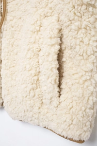 Detailed close-up showing the soft texture of cream sherpa fleece vest fabric