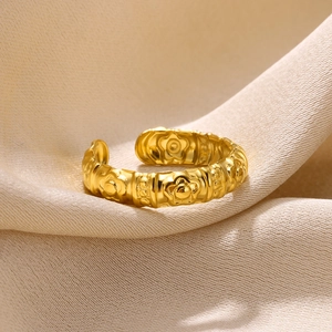 Macro detail of gold adjustable ring featuring embossed floral patterns on silk fabric
