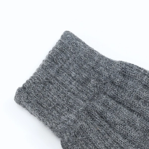 Macro shot of gray knitted gloves showing detailed wool blend texture and cable pattern