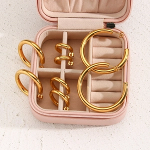 Close-up of assorted gold chunky hoop earrings displayed with a pink travel jewelry box