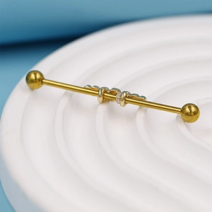 Vue macro d'un piercing industriel doré avec des anneaux décoratifs coulissants