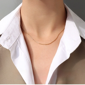 Detail of 1mm gold square bead chain necklace worn with a blazer for office style