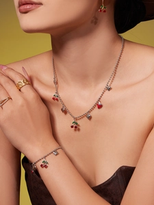 Détail du collier à perles argentées avec pendentif cerise et cœur et bracelet assorti