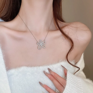 Close-up of a silver floral pendant necklace with sparkling crystals worn by a model