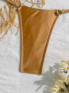 Detail of metallic champagne bikini bottom with side silver rings and satin sheen