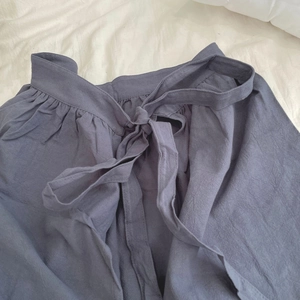 Detail of grey-purple cotton apron showing textured fabric and drawstring waist bow