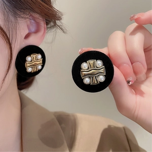Macro shot of vintage black flocked earrings with gold embossing and faux pearls
