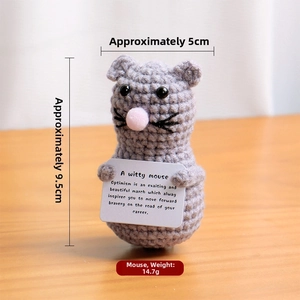 Macro shot of hand-crocheted gray mouse plush toy holding an encouraging message card