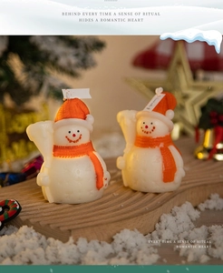 Two snowman scented candles with orange hats and scarves on a wooden tray for Christmas