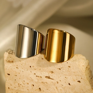 Polished wide gold and silver stainless steel rings on a stone and silk background