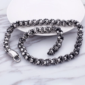 Detailed close-up of a silver punk skull chain bracelet on a marble background