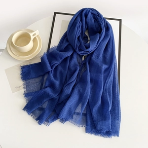 Royal blue linen scarf with crinkle texture and fringe edges on a white table