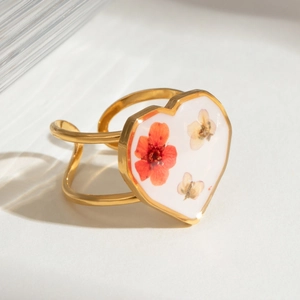 Detailed close-up of golden heart ring featuring real red and yellow dried flowers