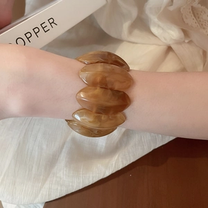 Close-up of a brown amber marble resin bracelet worn on a wrist in a cozy setting