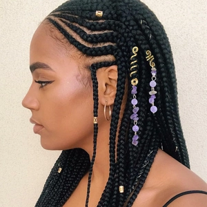 Detail of gold spiral hair rings and purple beaded chains on braided hair accessory