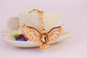 Golden eagle keychain with large brown crystals and pink gemstones hanging on a tea cup