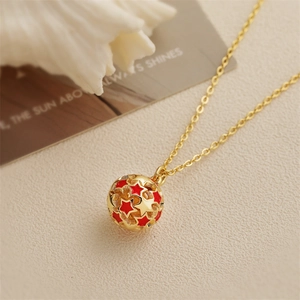 Chic gold necklace with star-patterned ball pendant on a soft textured background