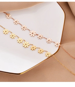 Detail of rose gold daisy charm bracelets on white ceramic dish and brown fabric