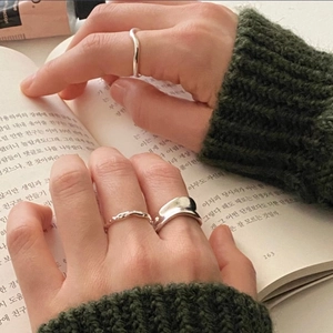 Close-up of irregular wave and woven 925 silver rings on hand with knit sweater