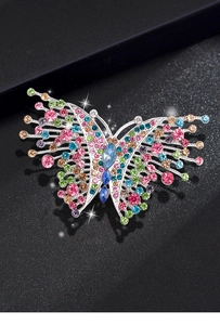 Macro close-up of colorful rhinestone butterfly brooch with sparkling crystals on black background