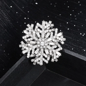 Elegant silver snowflake brooch with sparkling crystals on black wooden display stand