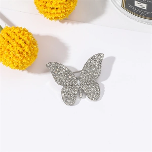 Close-up of sparkling rhinestone butterfly brooch on silver base with floral background
