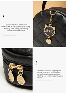 Detail of black quilted round bag with gold cat pendant and smooth metal zipper