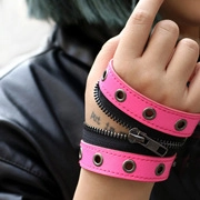 Detail of rose red and black PU leather punk bracelet with metal eyelets and zipper