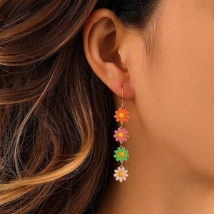 Detailed close-up of colorful daisy drop earrings worn by a model in vibrant floral style