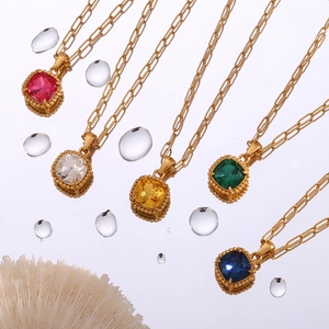 Gold paperclip chain necklaces with colorful square gemstones on a water-textured background
