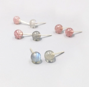 Macro detail of round natural strawberry quartz and moonstone silver stud earrings