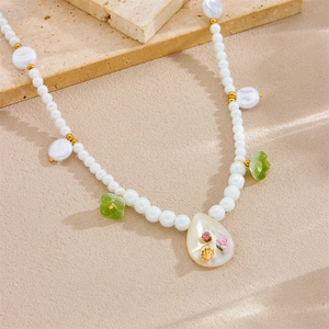 Detail of beaded pearl necklace featuring ocean shells and floral pendants on stones