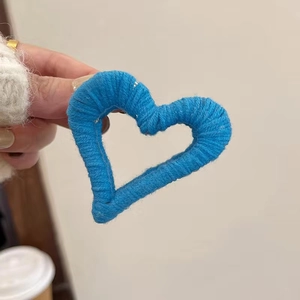 Detailed close-up of a blue handmade knit heart-shaped hair claw clip with wool texture