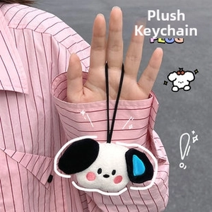 Close-up of cute plush dog keychain with sunglasses on a pink striped background
