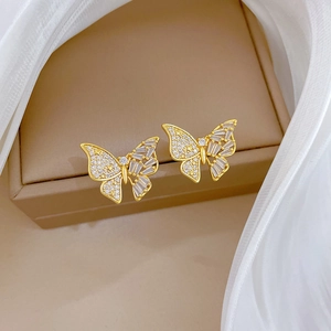 Gros plan de boucles d'oreilles papillon dorées avec zircons sur boîte à bijoux