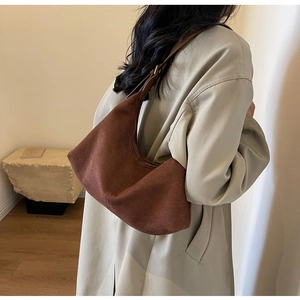 Deep brown matte suede crescent shoulder bag shown on model for size perspective