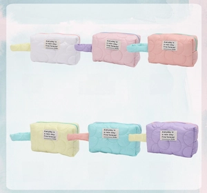 Macro view of six pastel quilted cosmetic pouches with soft fabric and top zippers